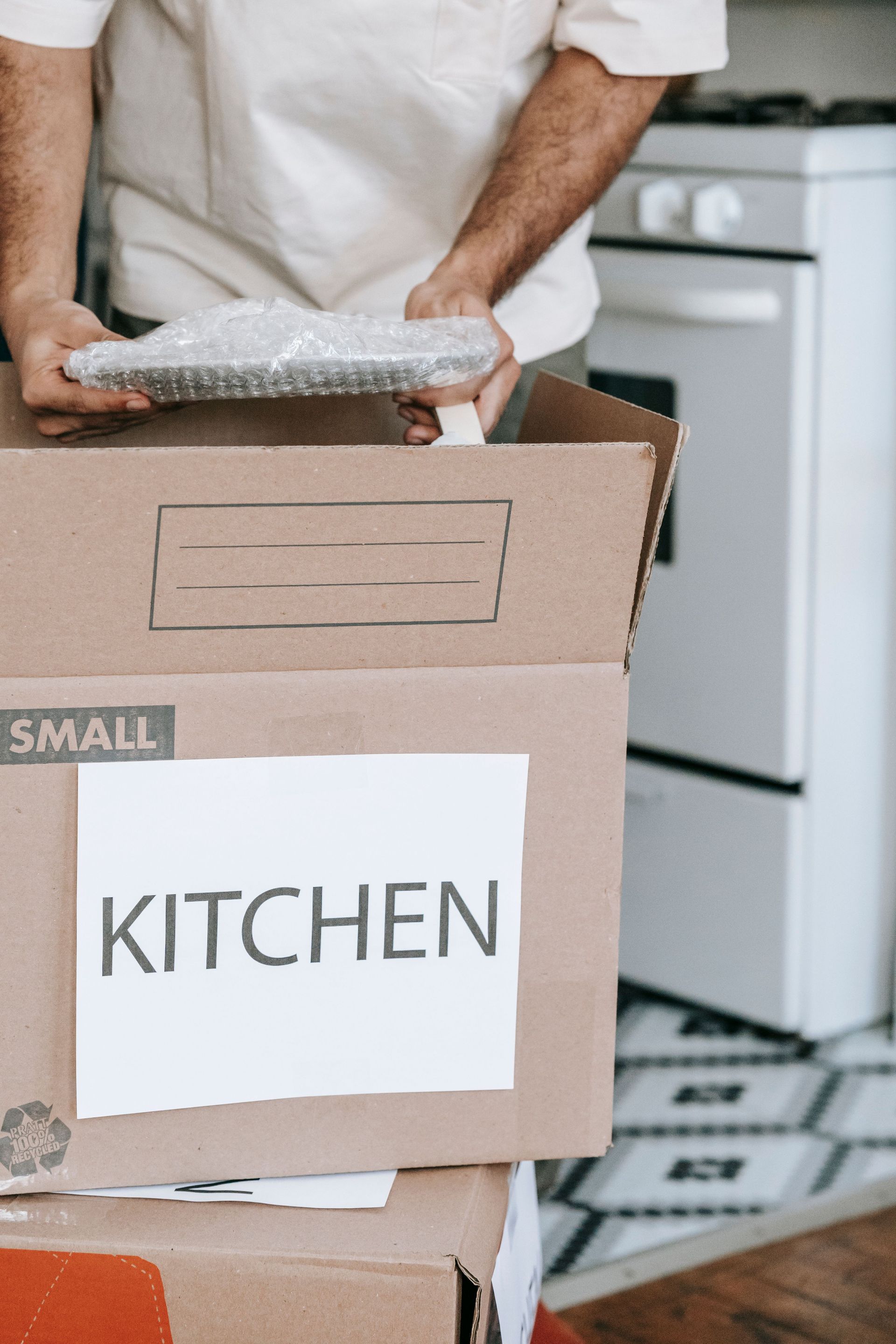 Man packing kitchenware into labeled boxes for a home relocation.
